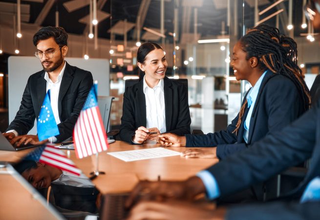 The flags of the USA and the European Union are on the table during negotiations between diplomats and businessmen. Representatives discuss relations between countries, signing a treaty.