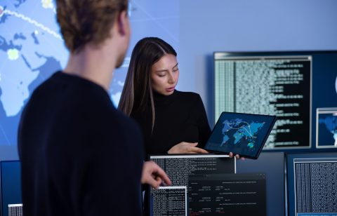 Cyber security team working in a Cyber Security Operations Center (SOC). Woman work as Chief Information Security Officer (CISO) and manager pointing on a real time map om tablet.