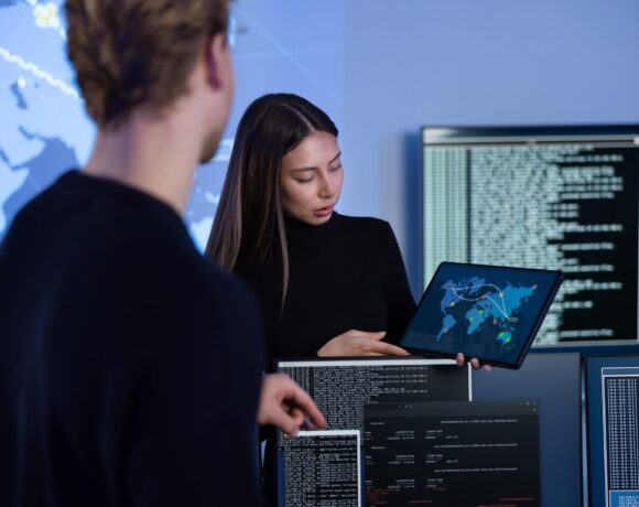 Cyber security team working in a Cyber Security Operations Center (SOC). Woman work as Chief Information Security Officer (CISO) and manager pointing on a real time map om tablet.